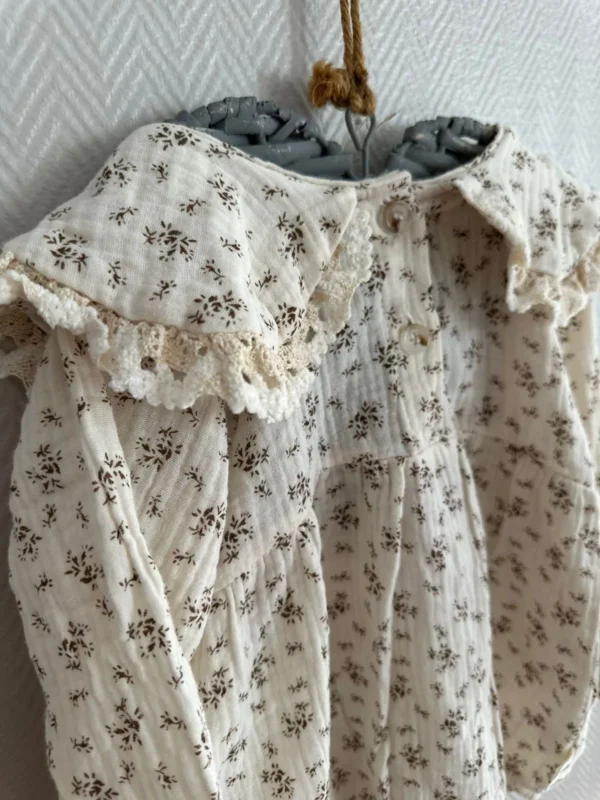 L'ensemble barboteuse chapeau Chocolatine, 100% coton, offre confort et style aux bébés de 3 à 12 mois. Disponible en blanc cassé avec imprimé fleuri marron, il est parfait pour les journées ensoleillées.4